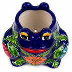 A ceramic frog-shaped planter pot with a glossy dark blue body, hand-painted green leaves, orange and red flowers, and yellow eyes on a white background.