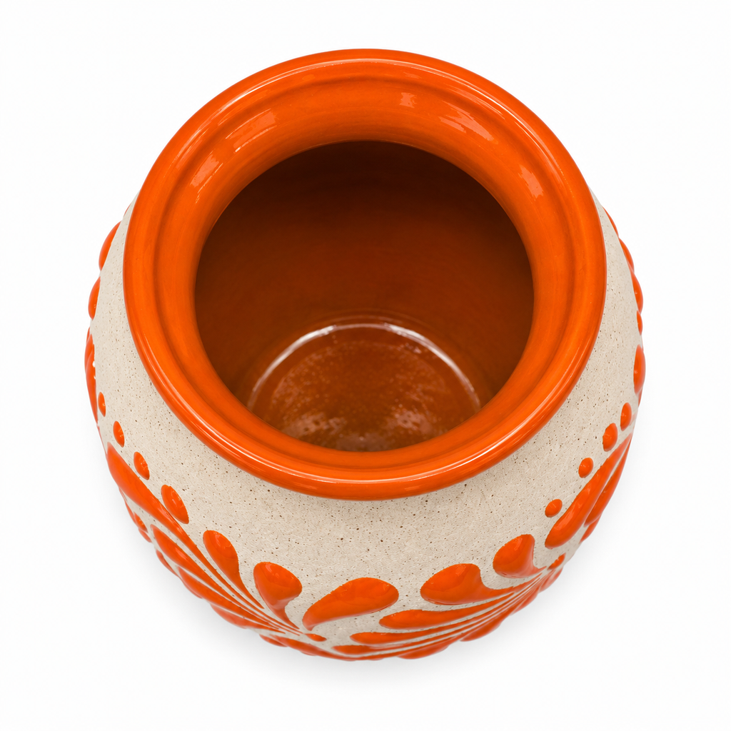 A ceramic pot with a glossy orange glazed interior and rim, featuring a speckled beige exterior decorated with orange leaf-like patterns and small dots, shown from a top-down view on a white background.