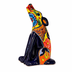 A colorful ceramic figurine of a howling dog, decorated with vibrant hand-painted patterns in yellow, blue, red, orange, and black on a plain white background.