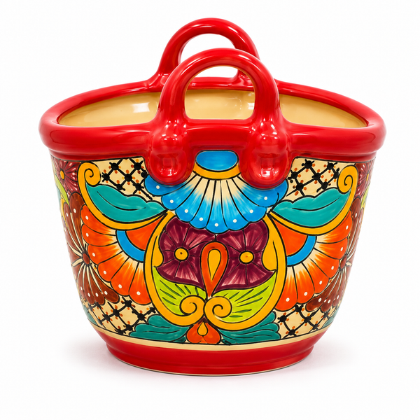 A colorful ceramic basket-shaped planter with red handles and a hand-painted traditional pattern in orange, blue, green, yellow, and purple on a white background.
